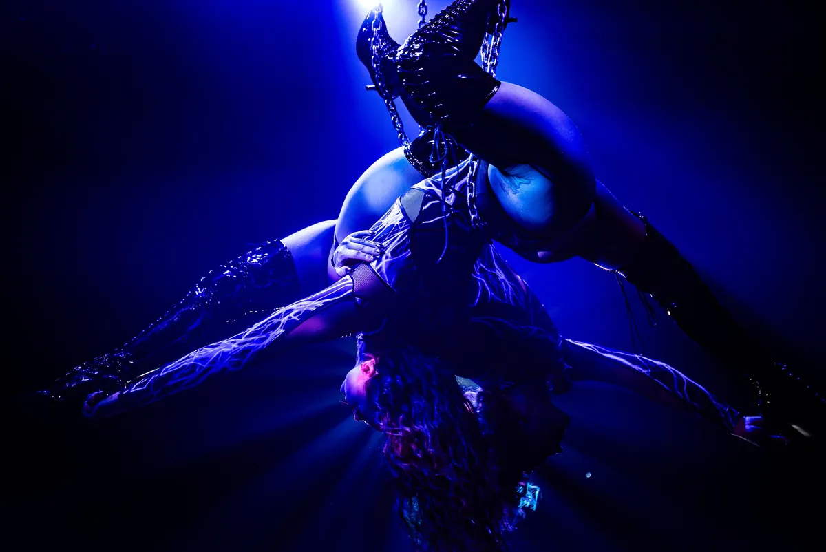 An aerial performer upside down on a chain rig in blue light at the Broadbeach cabaret