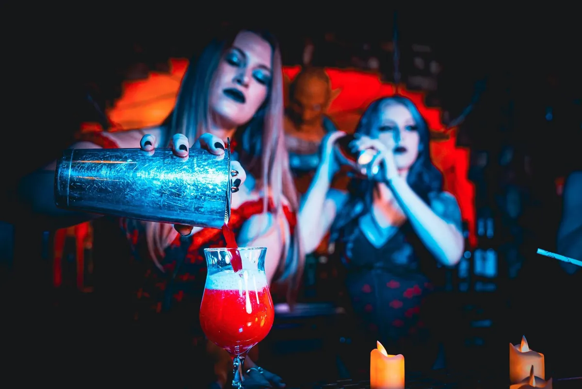 Two costumed performers pour a red cocktail by candlelight at Dracula's Gold Coast