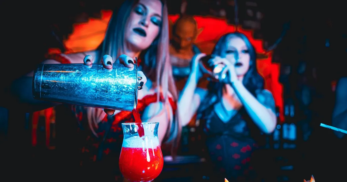 Two costumed performers pour a red cocktail by candlelight at Dracula's Gold Coast
