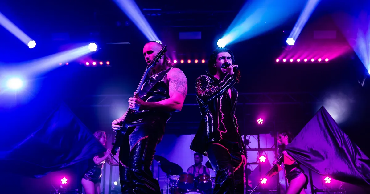 A rock band and dancers on stage under blue spotlights during the Dracula's Gold Coast show