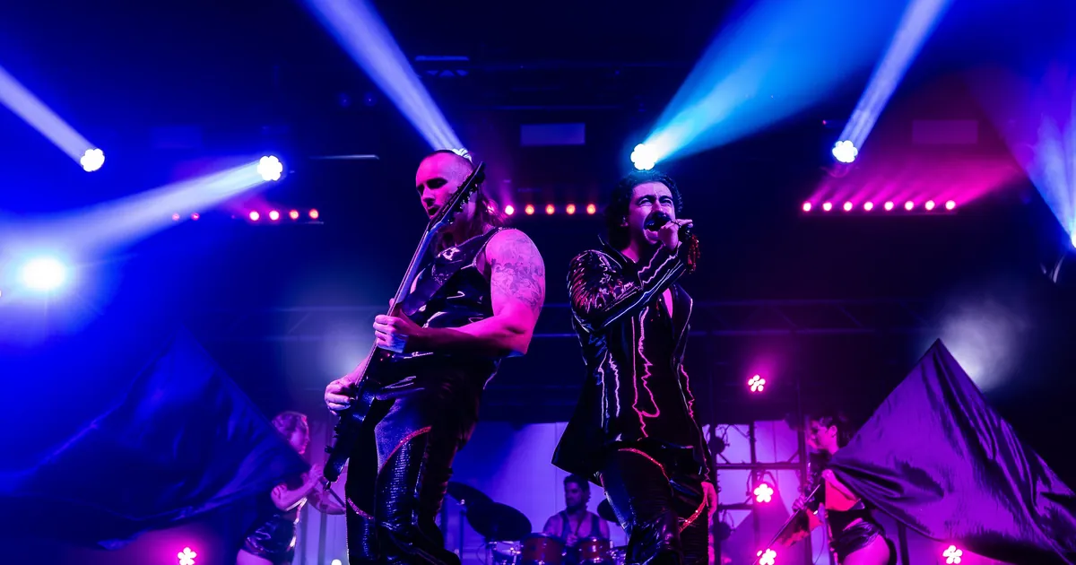 A rock band and dancers on stage under blue spotlights during the Dracula's Gold Coast show